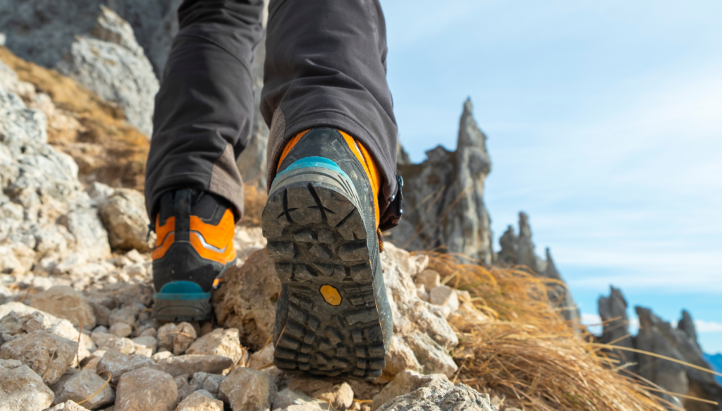 Picture of persons hiking boots along a cliff with blue sky in the background