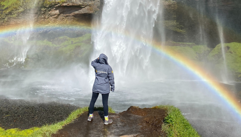 Picture of students standing behind a waterfall in Iceland