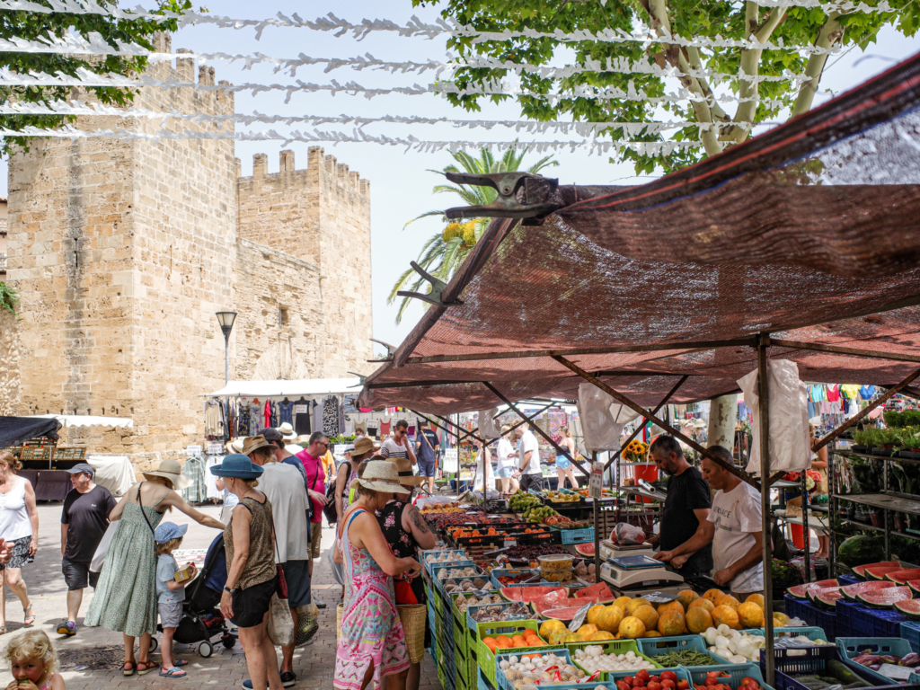 Picture of people at a market in spain with a castle in the background