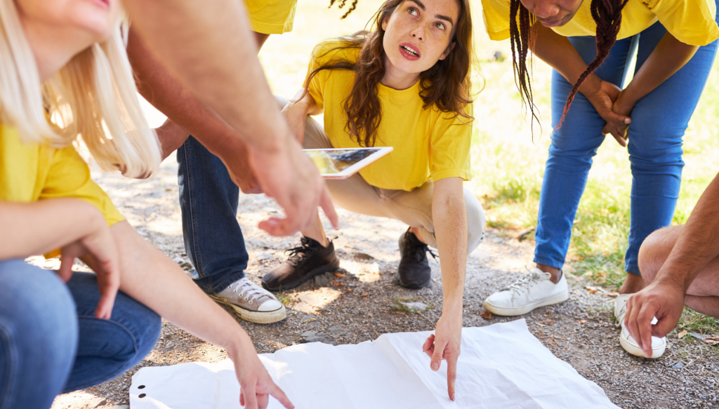 Picture of students looking at a large piece of paper on the ground. A couple of people are pointing to the paper